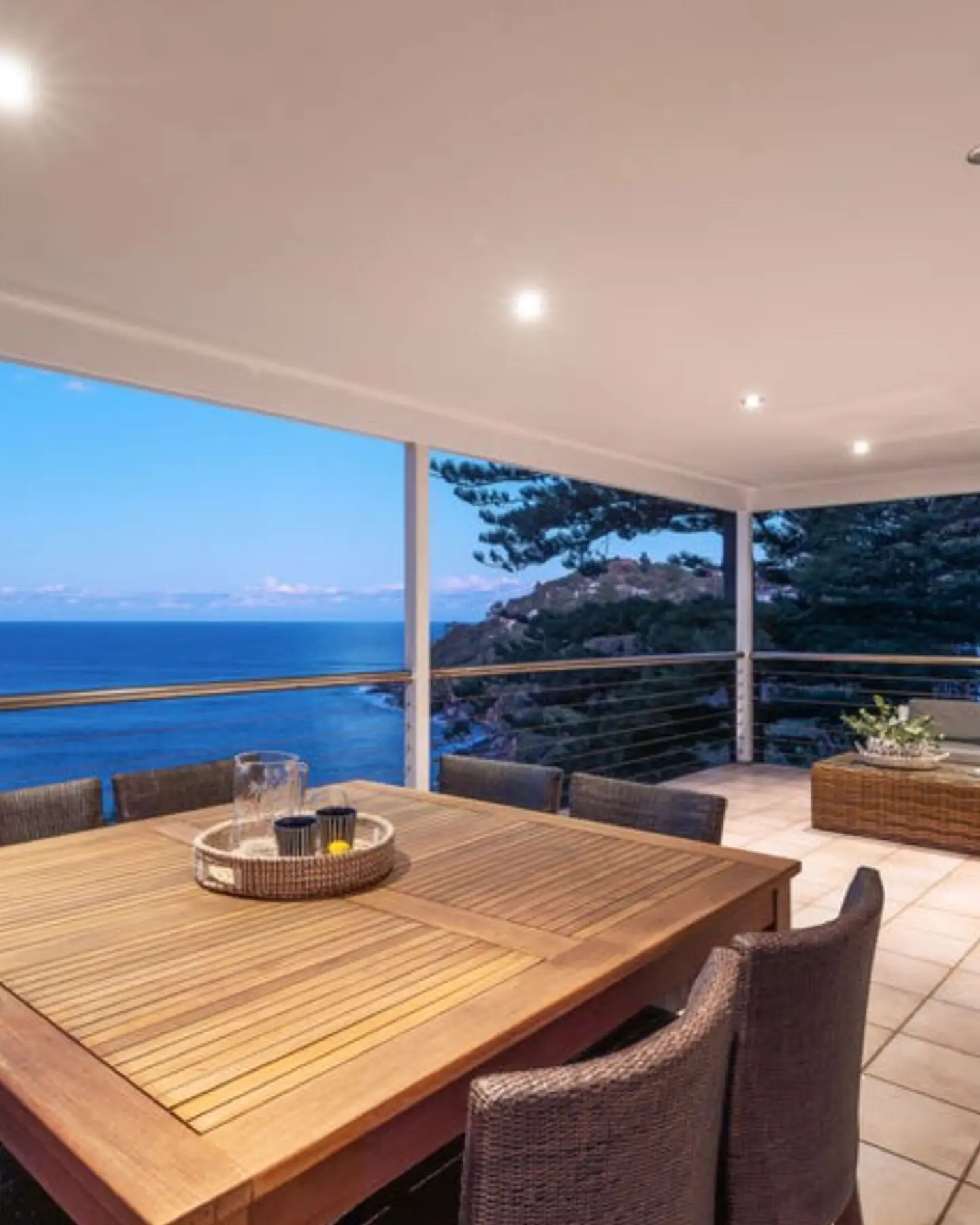 Large outdoor entertaining balcony at dusk with coastal views, illustrating the type of executive properties we purchase