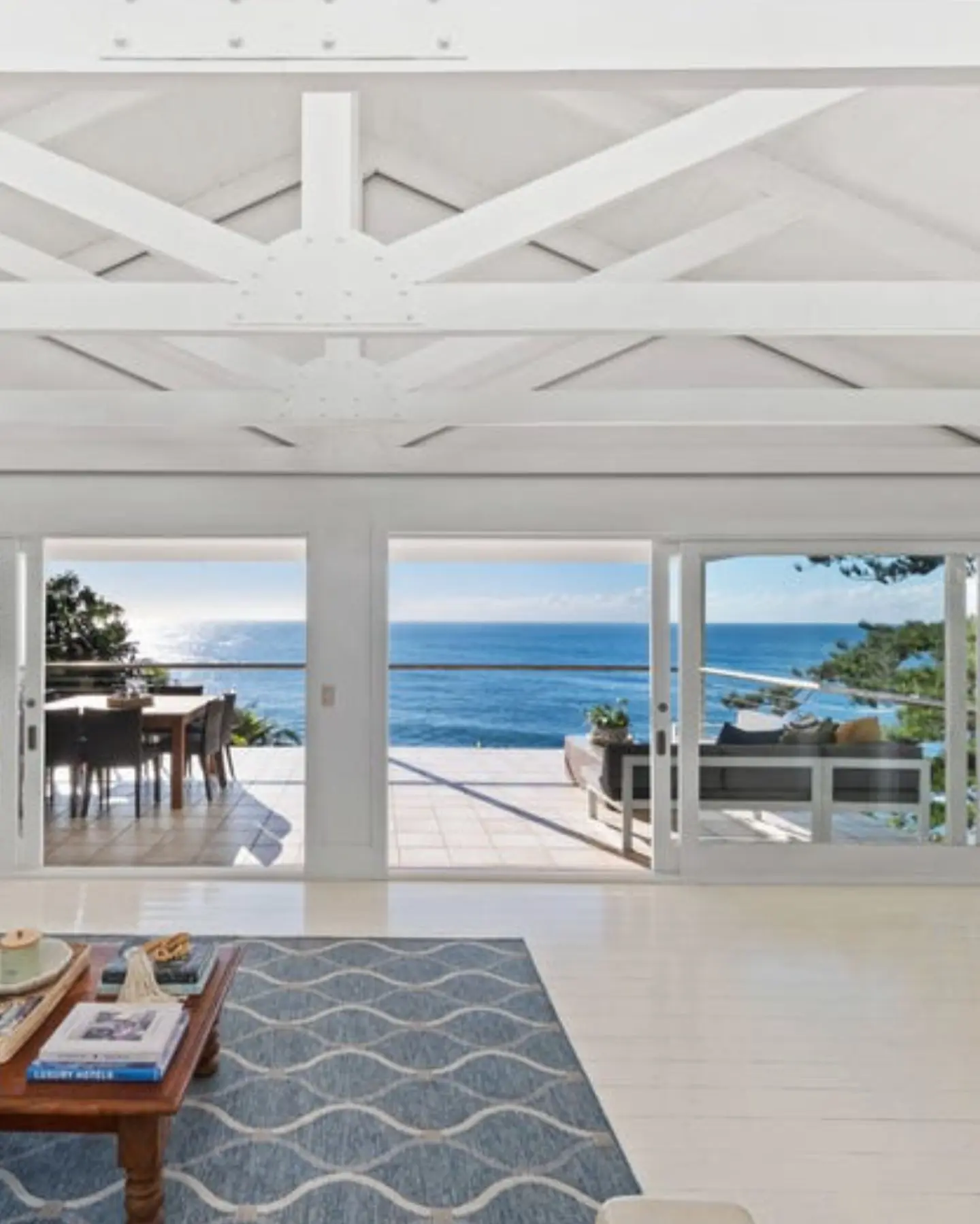 A bright, expansive luxury living room with high ceilings and sweeping coastal views, representing the calibre of prestige homes we purchase as we expand into the Upper and Lower North Shore