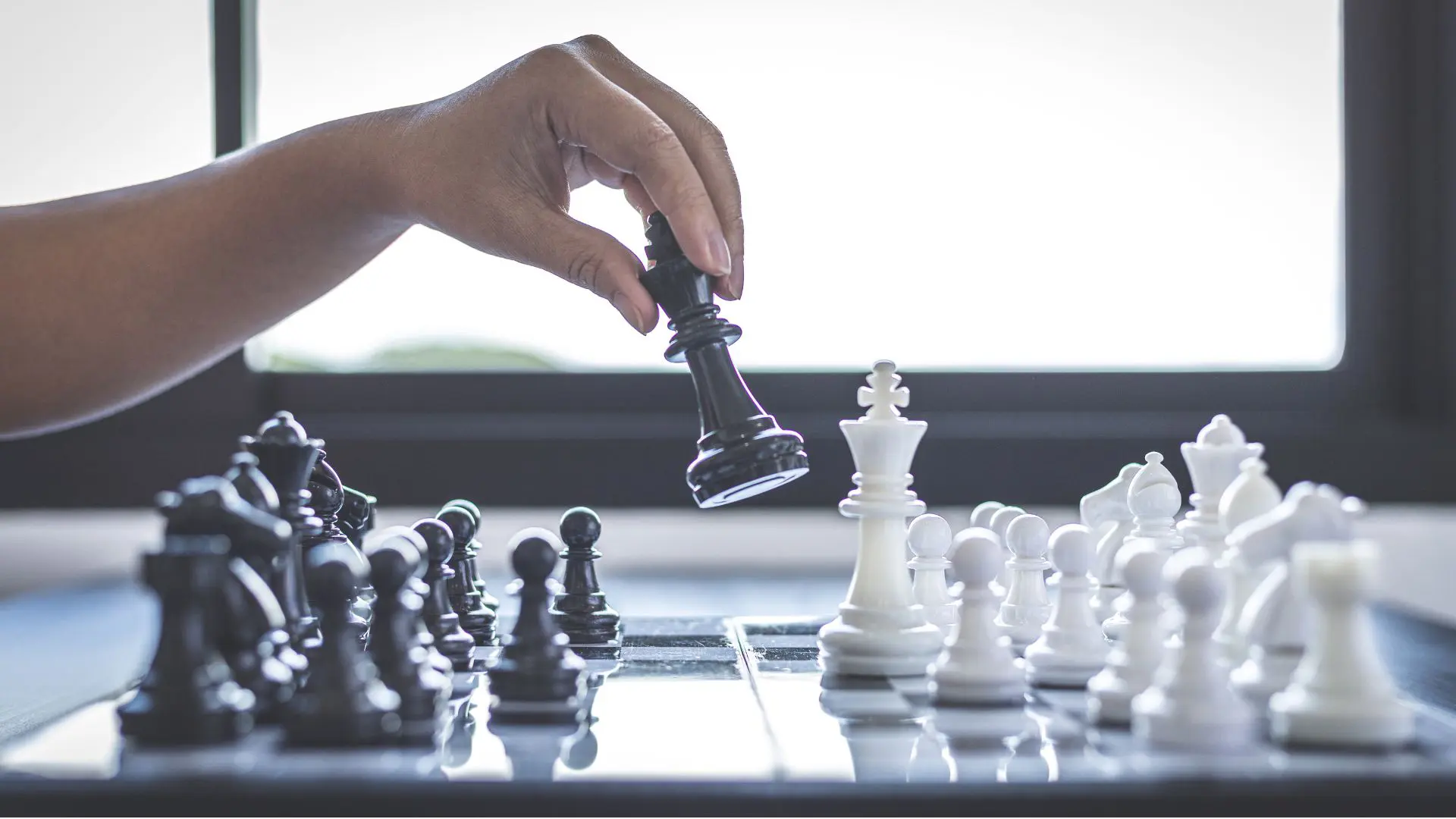 A hand making a decisive move on a chessboard, symbolising the strategic negotiation power and unfair advantage Sarah Kaye & Co secures for property buyers