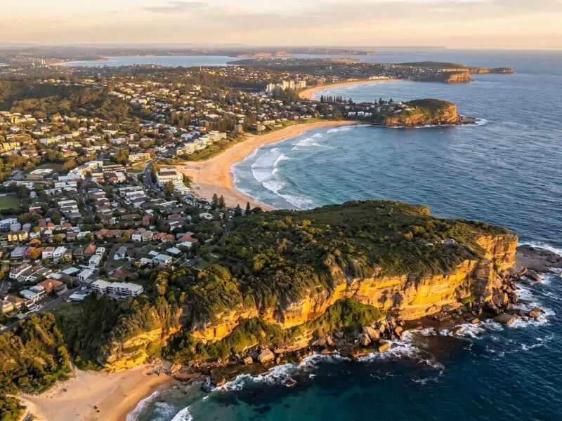 Aerial view of Sydney's Northern Beaches coastline at golden hour, looking north from Manly along the residential headlands