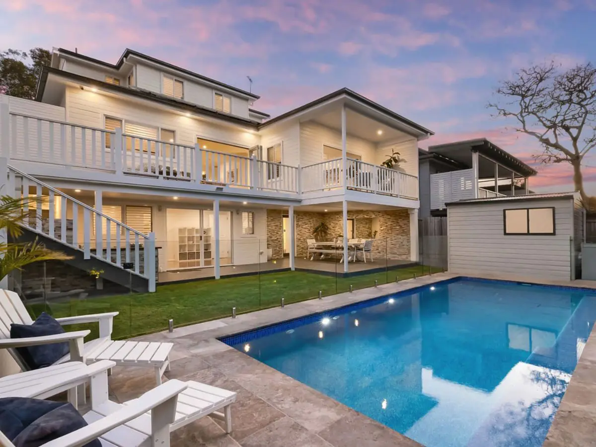 Two-storey weatherboard house with pool and rear deck at dusk on Amourin Street, North Manly, bought for a client before it was listed