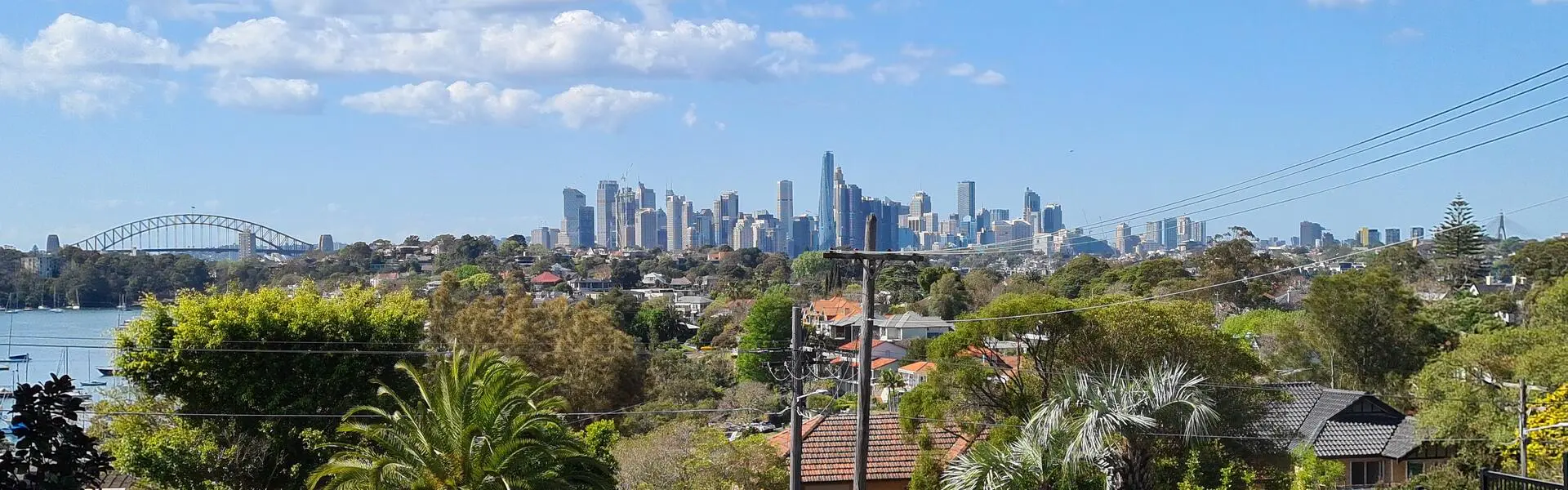 A Longueville street looking over houses and gardens towards the Harbour Bridge and the Sydney city skyline